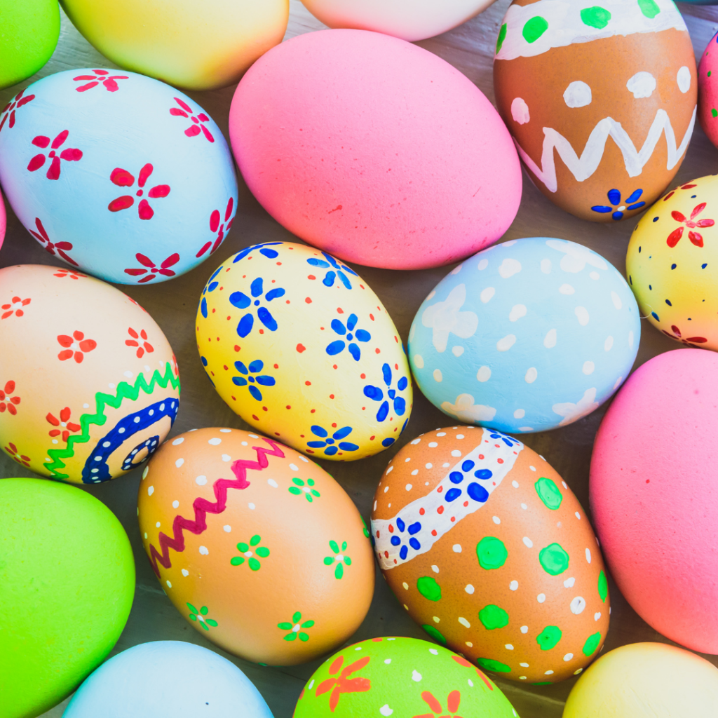 An image of colourful eggs that are hand painted for easter. Painted on the eggs are flowers and dots in blues, reds and greens. The eggs backgrounds are pink, blue, yellow and brown.