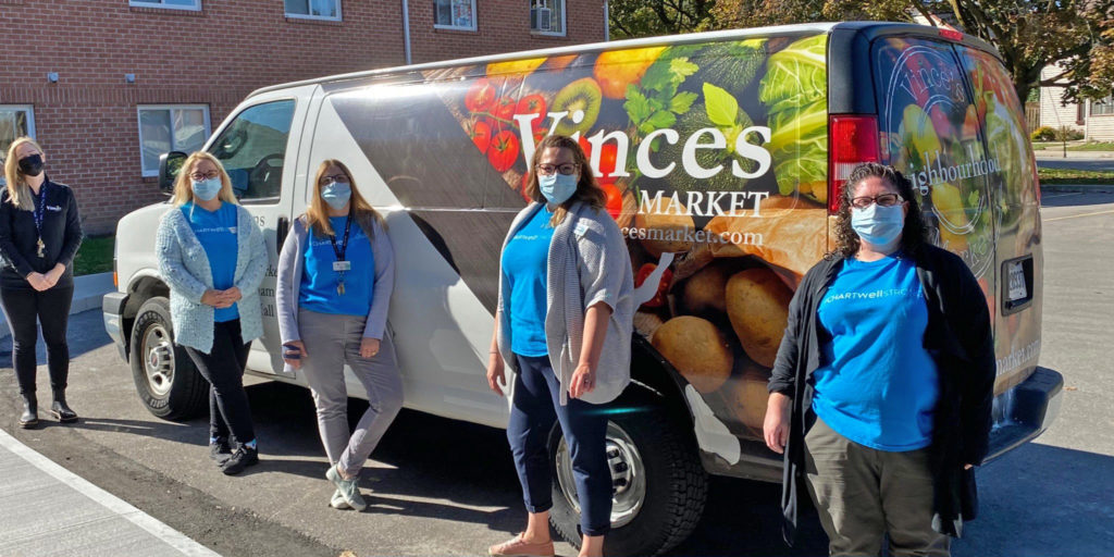 Image of Vince's employees standing in front of a van that has Vince's logo on it. Everyone is wearing masks.
