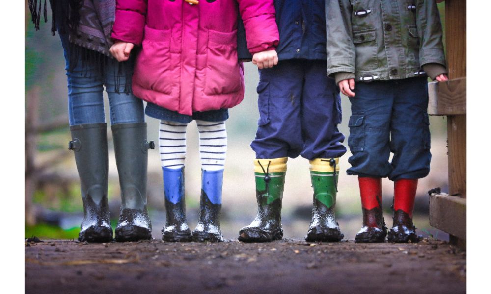 image of 4 children standing in mud. The photo only shows the legs. The children are wearing rain boots. Image is for the blog post for Vince's Toonies for Tummies