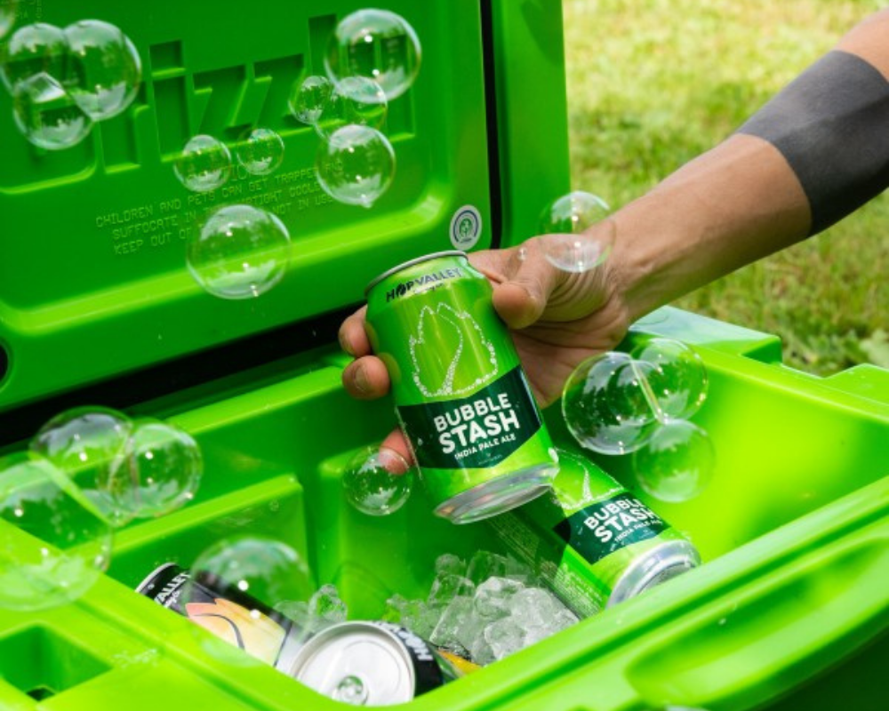 Image of someone taking out a Hop Valley Bubble Stash IPA from a green cooler with bubbles flying around