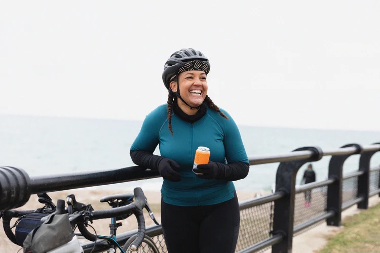 Woman enjoys a Rally Beer while taking a break from biking
