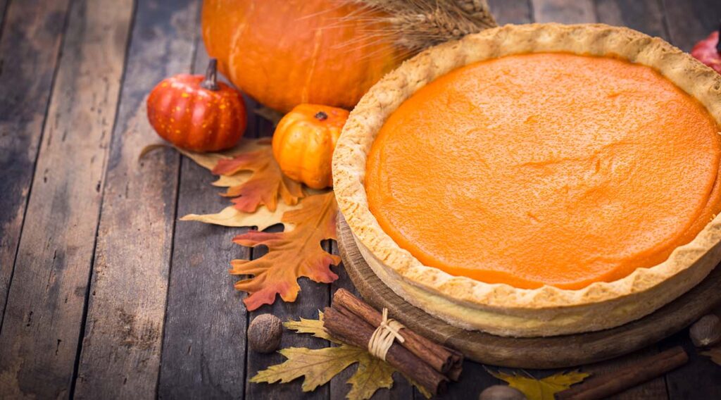 pumpkin pie surrounded by gourds and Fall leaves