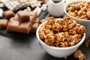 Two bowls of caramel popcorn and a stack of caramel.