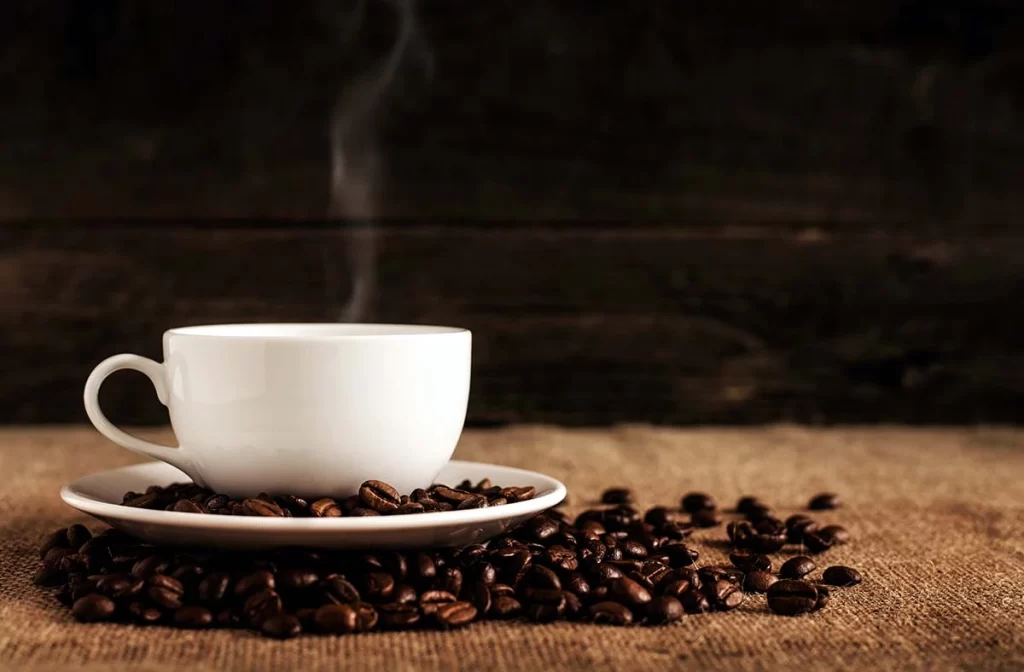 Cup of hot coffee on roasted coffee beans
