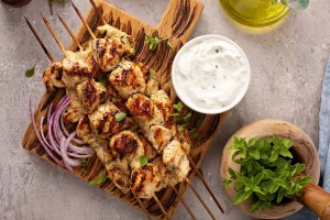 Chicken souvlaki skewers with a small bowl of tzatziki