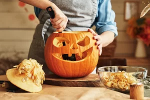 A person carving a pumpkin to make a jack o lantern. Making halloween easy with Vince's removes the hassle and leaves time for activities like this.