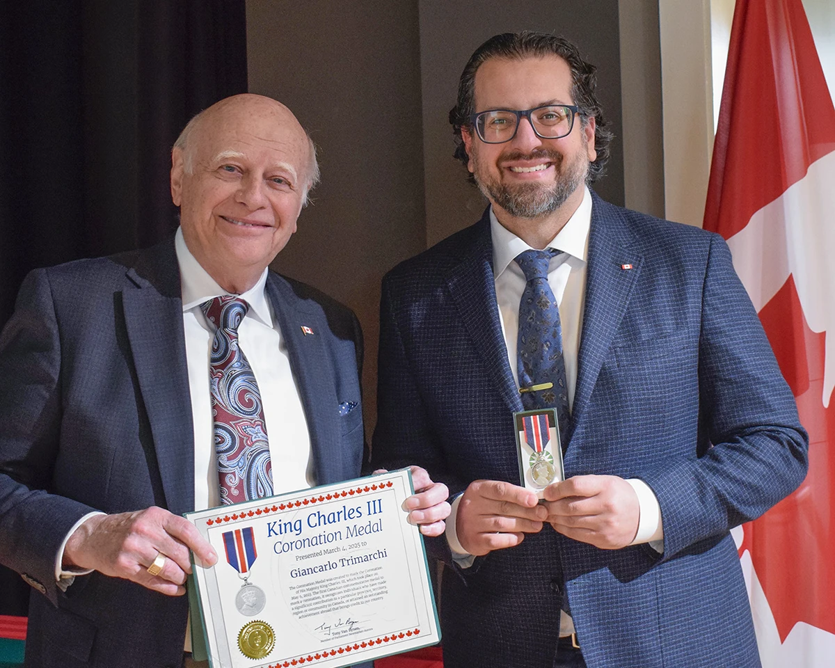 Giancarlo holds the King Charles III coronation medal standing next to Tony van Bynen, local MP, holds the official certificate.